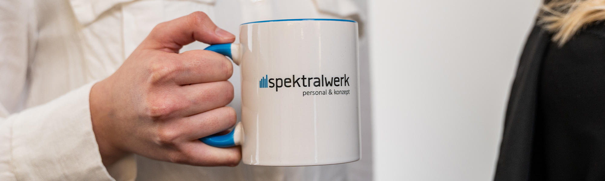 Eine Hand hält eine Spektralwerk Tasse